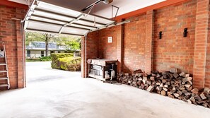 A garage with a brick wall, a woodpile, and a metal workbench. - SHINE BRIGHT - Spacious family friendly group living in Bright (Bright)