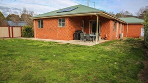 A brick house with a green roof, a patio with a table and chairs, and a covered grill area. - SHINE BRIGHT - Spacious family friendly group living in Bright (Bright)