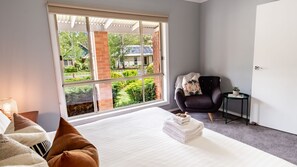 A modern bedroom with a large window, a bed, a chair, and a small table. - SHINE BRIGHT - Spacious family friendly group living in Bright (Bright)