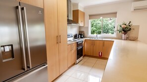 A modern kitchen with stainless steel appliances, wooden cabinets, and a window providing natural light. - SHINE BRIGHT - Spacious family friendly group living in Bright (Bright)