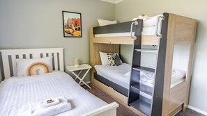 A bunk bed with a white headboard, a bedside table with a lamp, and a framed picture on the wall. - SHINE BRIGHT - Spacious family friendly group living in Bright (Bright)