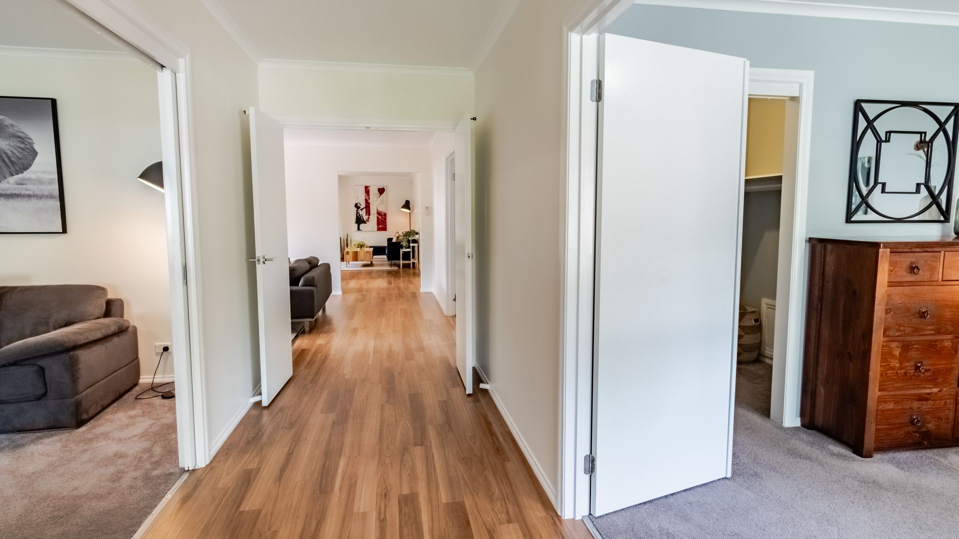 Ein Flur mit Holzboden, der in einen Wohnbereich mit einer Couch und einem Schrank führt.