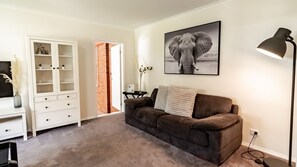 A living room with a brown sofa, a white cabinet, a framed elephant picture, and a floor lamp. - SHINE BRIGHT - Spacious family friendly group living in Bright (Bright)
