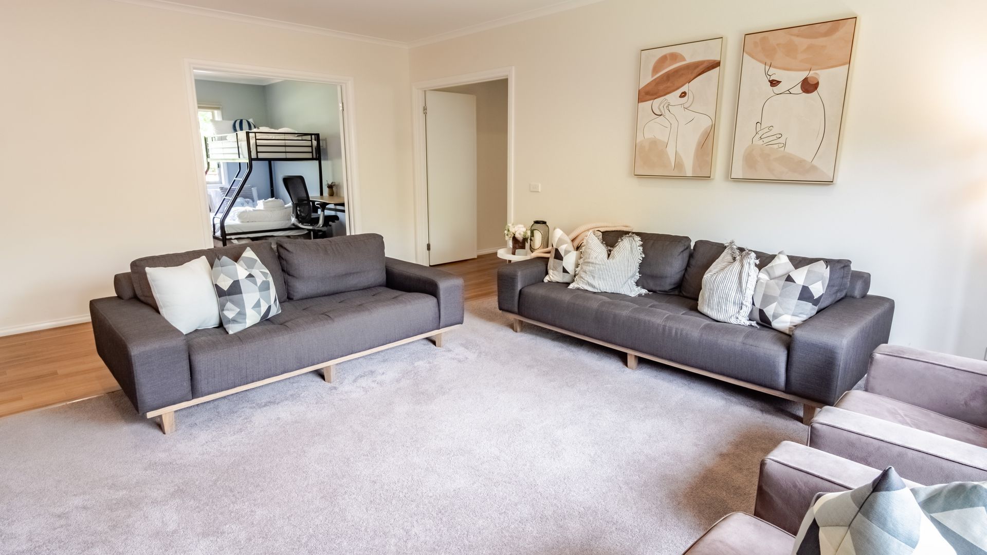 A living room with two grey sofas, a coffee table, and a rug. There are two doors leading to other rooms.