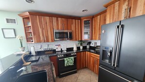 Una cocina con armarios de madera, un refrigerador de acero inoxidable, un microondas y un horno.