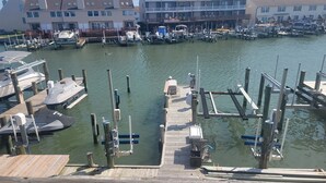 Un puerto deportivo con barcos amarrados, un muelle de madera y edificios residenciales al fondo.