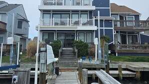 Una propiedad frente al agua con un muelle de madera que lleva a un edificio de dos pisos con balcones.