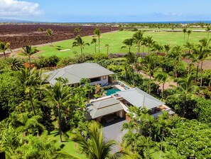 A residential property with a swimming pool, surrounded by lush greenery and a golf course in the background. - Champion Ridge #35: Paradisiac Home w/Infinity Pool, Hot Tub & Tropical Feeling (Kamuela)