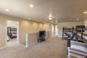 A room with bunk beds, a television, and a carpeted floor. - A Green Escape at The Ledges (St. George)