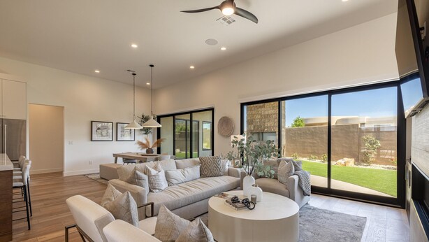 A spacious living room with a large sofa, a coffee table, and a dining area with a kitchen in the background. - The 19th Hole at The Ledges (St. George)