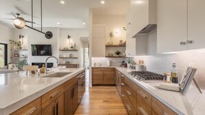 A modern kitchen with wooden cabinets, a large island, and a built-in stove. - The 19th Hole at The Ledges (St. George)