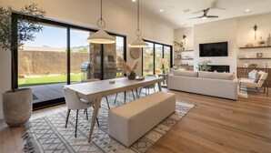 A modern living room with a dining area, large windows, and a ceiling fan. - The 19th Hole at The Ledges (St. George)