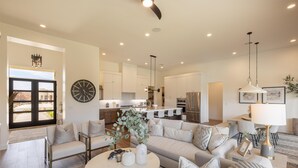 A spacious living area with a modern kitchen, a dining area, and a large window providing natural light. - The 19th Hole at The Ledges (St. George)