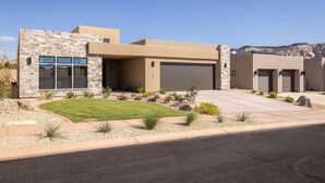 Une maison moderne à deux étages, dotée d’une façade en pierre, d’un garage et d’une pelouse bien entretenue.
