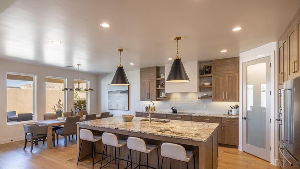 Une cuisine moderne dotée d’un grand îlot central, de luminaires suspendus et de meubles de rangement en bois.