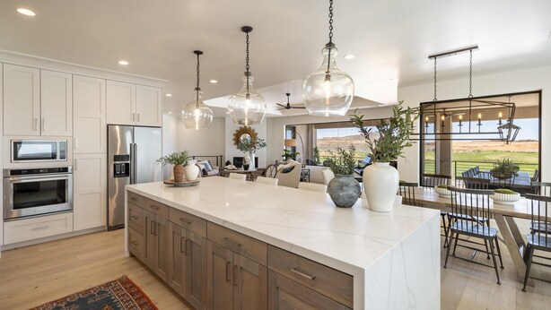 A modern kitchen with white cabinets, stainless steel appliances, and a large island. - Taking Flight (St. George)