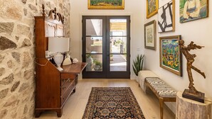 A stone wall, wooden furniture, a patterned rug, and various artworks on the walls. - Taking Flight (St. George)