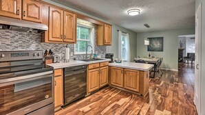 A modern kitchen with wooden cabinets, stainless steel appliances, and a herringbone wood floor. - Charming Pentwater Home w/ Fire Pit & Yard! (Pentwater)