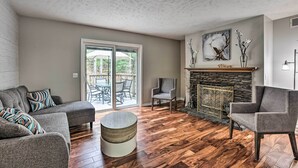 A living room with a fireplace, a sofa set, a round coffee table, and a dining area with outdoor seating. - Charming Pentwater Home w/ Fire Pit & Yard! (Pentwater)