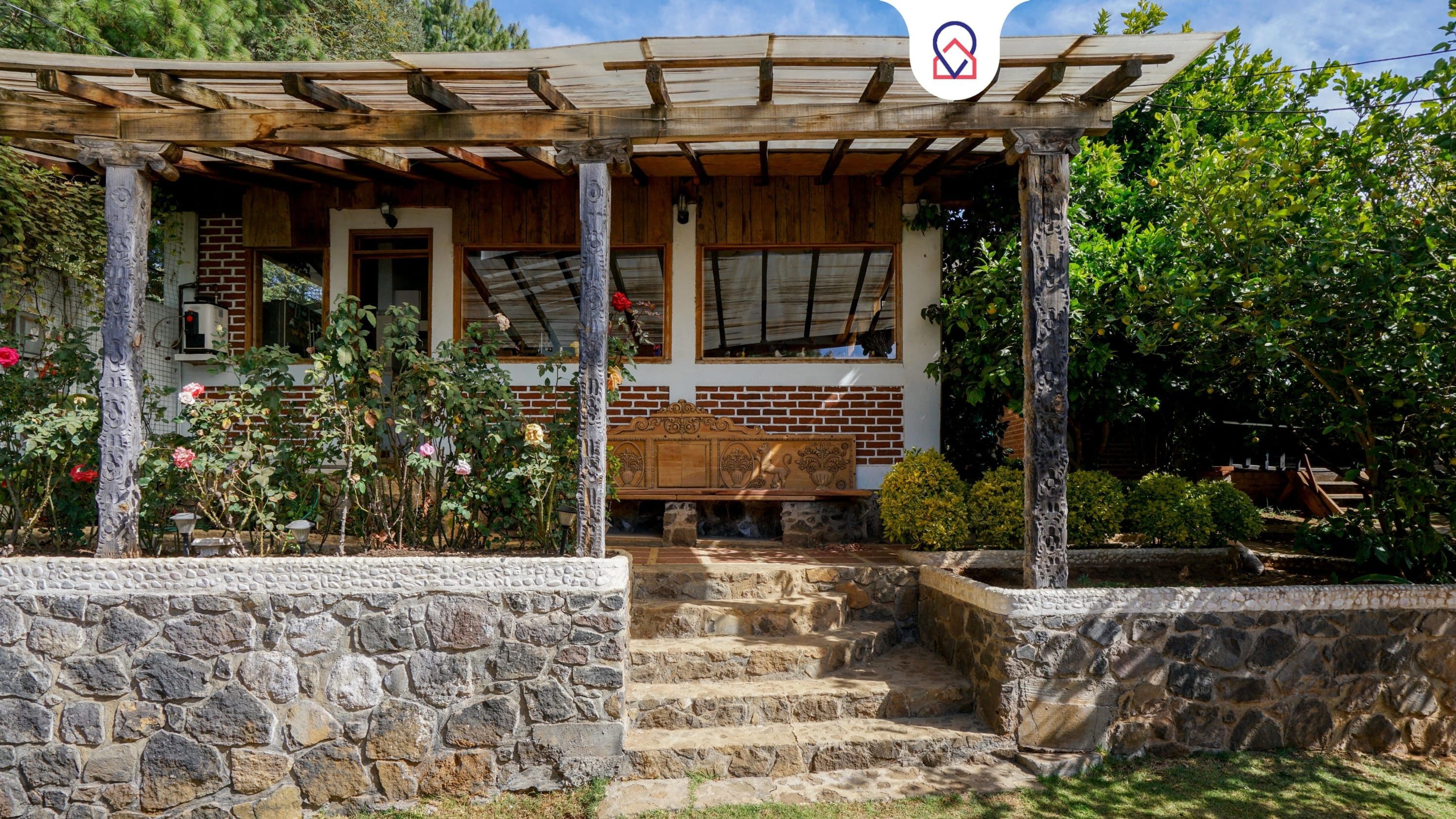 A stone-walled building with a wooden porch and a bench.
