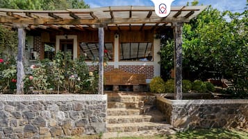 A stone-walled building with a wooden porch and a bench.