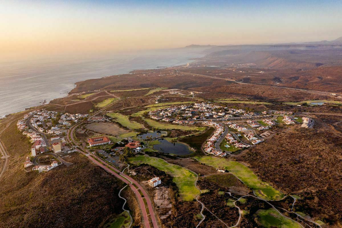 An aerial view of a coastal resort with a golf course, a marina, and a small town layout.