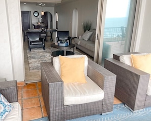 Relax in this inviting living area with a sofa, chair, and small table, offering a view of the outdoors through the glass door.