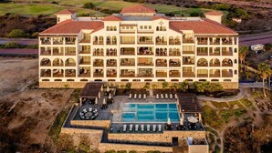 A large, multi-story hotel with a central courtyard and a swimming pool. - Ocean View Oasis at Bajamar Resort (Ensenada)