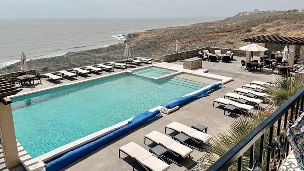 A pool area with lounge chairs and umbrellas, overlooking a coastal landscape. - Ocean View Oasis at Bajamar Resort (Ensenada)