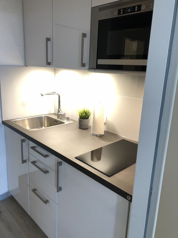 Una cocina moderna con electrodomésticos de acero inoxidable, un lavamanos doble y un horno empotrado.