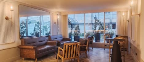 A spacious living area with a large window, a sofa, chairs, and a dining table.