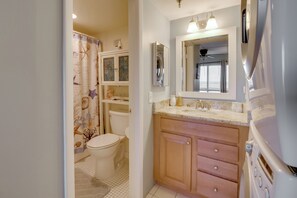 Un baño pequeño con inodoro, cortina de ducha y lavamanos integrado con espejo.