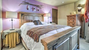 A bedroom with a wooden bed, two bedside tables with lamps, a dresser, and a wall-mounted branch decoration.