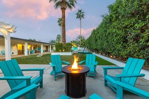 A patio area with a fire pit, outdoor seating, and a view of a building with a covered patio.