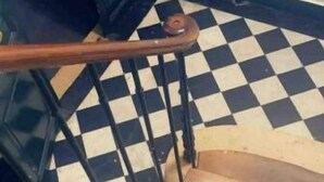 Un escalier avec un sol à carreaux noirs et blancs et une main courante en bois.