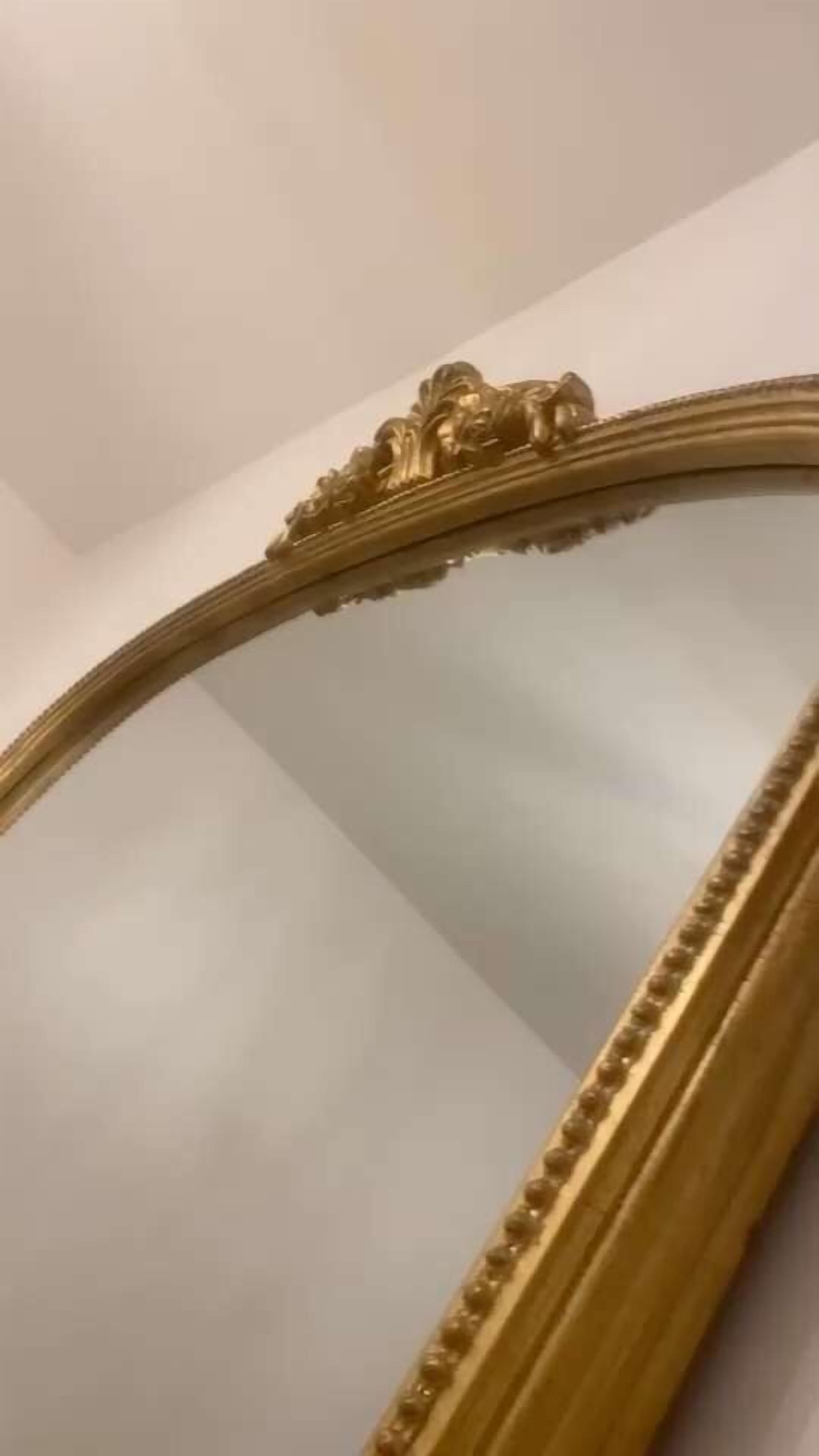 A gold-framed mirror with ornate detailing.