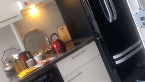 Une cuisine de taille réduite équipée d’un lave-linge, d’une cuisinière et d’un réfrigérateur.