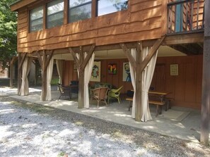 A wooden cabin with a covered patio area featuring outdoor seating and artwork.