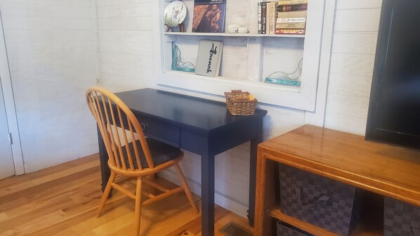 A room with a wooden chair, a dark blue desk, and a bookshelf with various books and decorative items.
