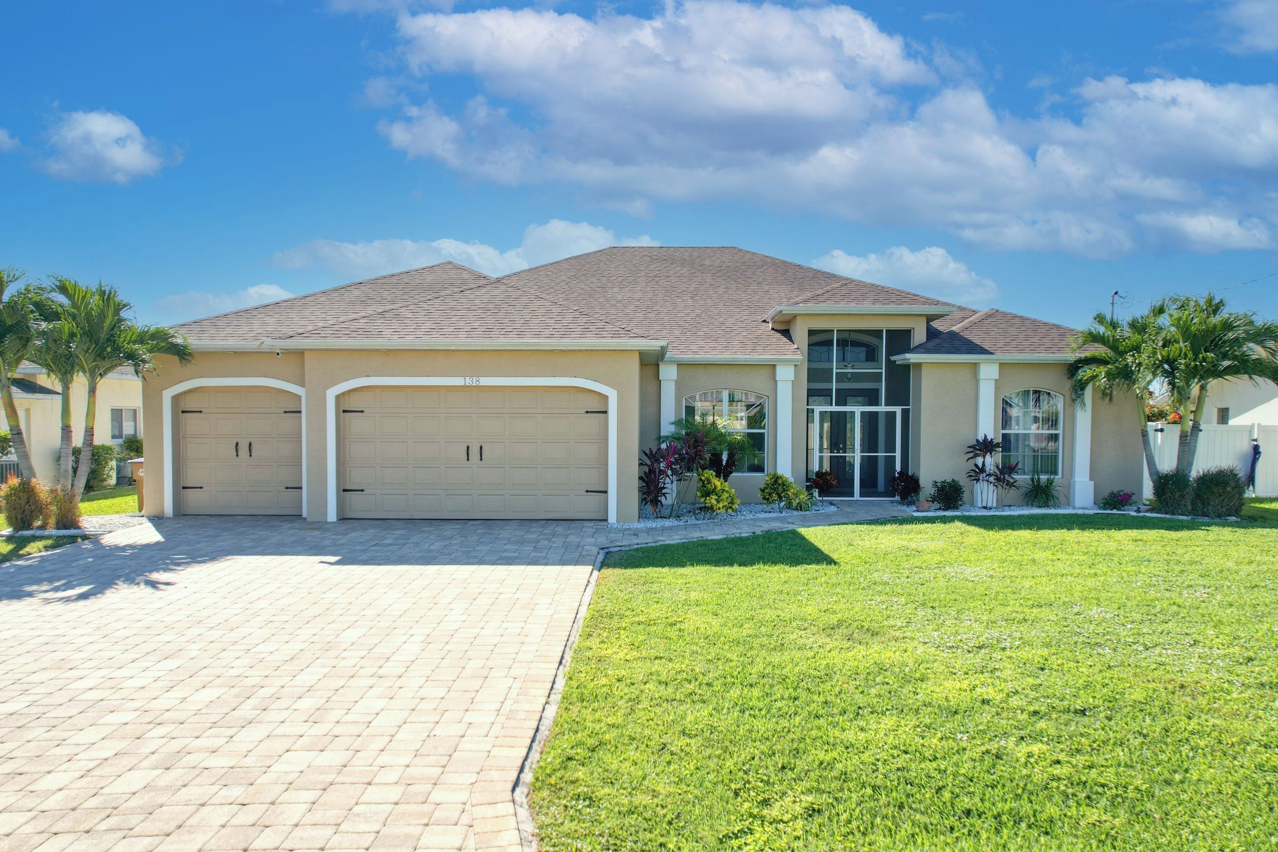 A two-story house with a garage, a well-maintained lawn, and a clear sky.