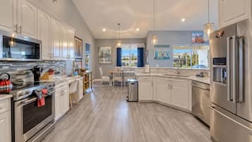 A modern kitchen with stainless steel appliances, a dining area with a view, and a clean, light wood floor.