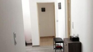 Un pasillo estrecho con piso de madera, un banco y un armario oscuro.
