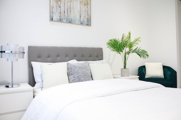 Relax in a serene bedroom with a large bed, bedside table, and comfortable armchair.