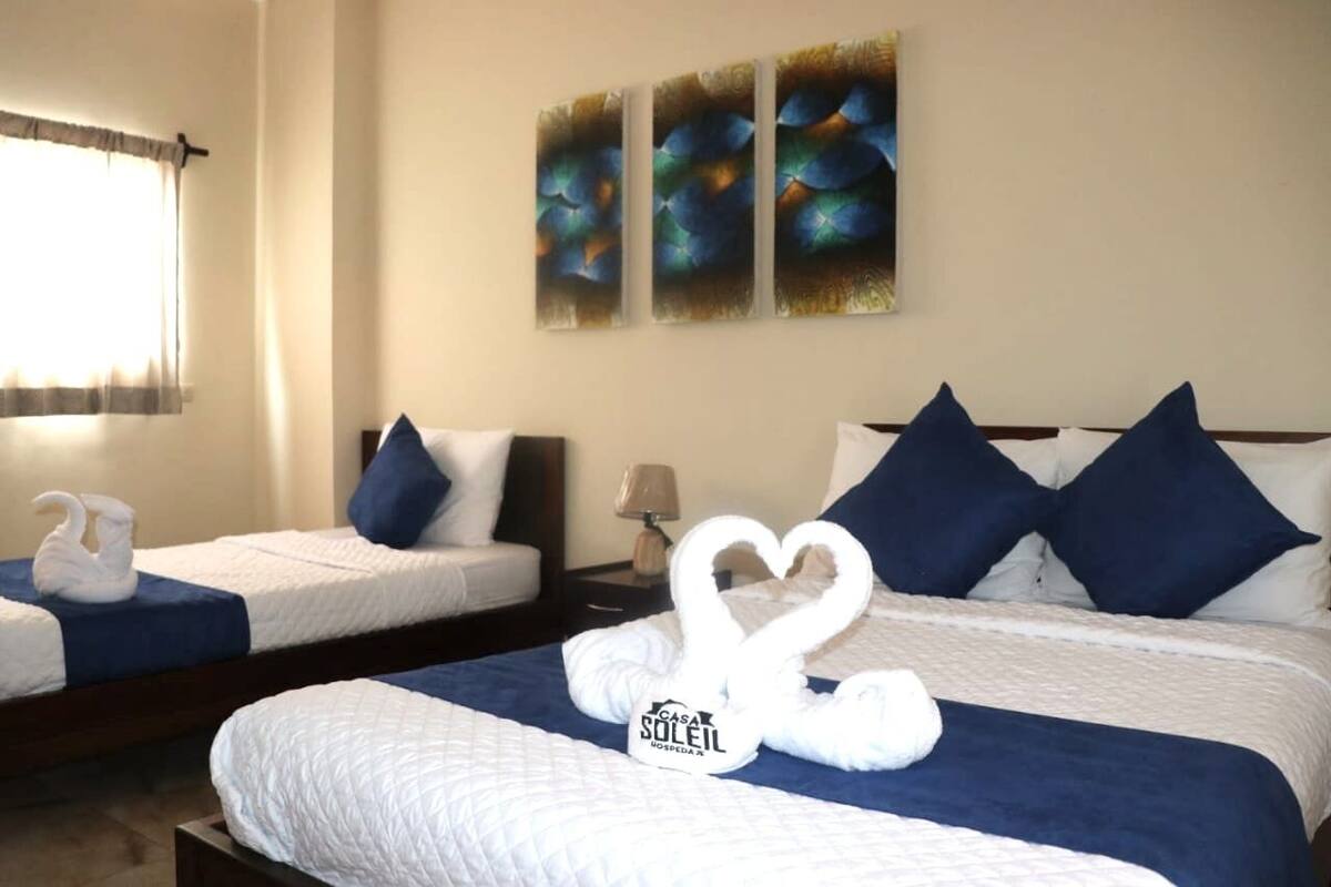 A hotel room with two beds, each with a heart-shaped towel arrangement and a sign reading "CASA SOLEIL."