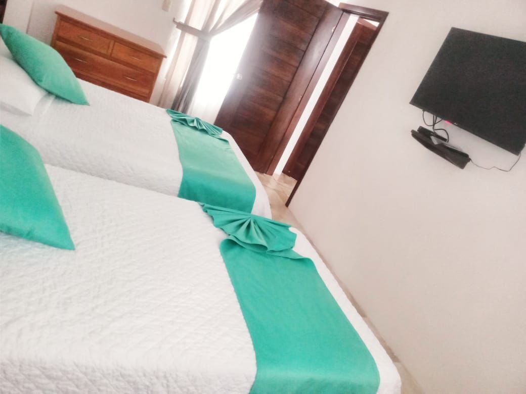 Un dormitorio con dos camas, un armario de madera y un televisor en la pared.