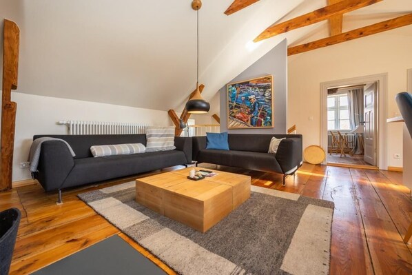 En moderne stue med en mørk sofa, et træsofabord og et stort maleri på væggen.