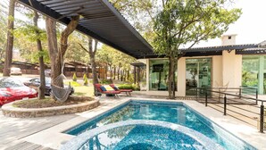 Un espace piscine extérieur moderne, doté d’un jacuzzi orné de mosaïques, de chaises longues et d’une pergola.