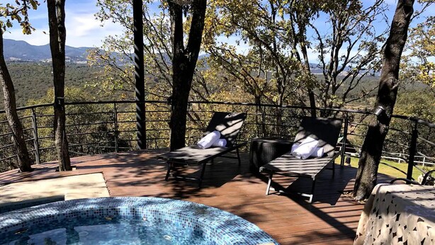 Un bain à remous entouré de chaises longues et une terrasse en bois offrant une vue sur les montagnes.