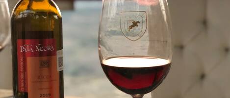 Una botella de vino Pata Negra y una copa de vino tinto sobre una mesa con mantel de encaje.