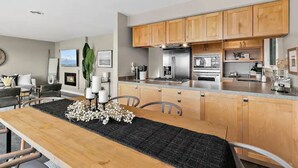 Una cocina moderna con armarios de madera, electrodomésticos de acero inoxidable y un comedor con mesa y sillas de madera.